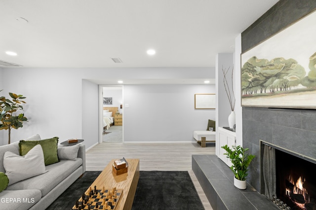 living room featuring a tiled fireplace and wood-type flooring