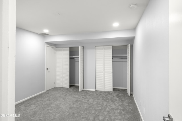 unfurnished bedroom with multiple closets and carpet flooring