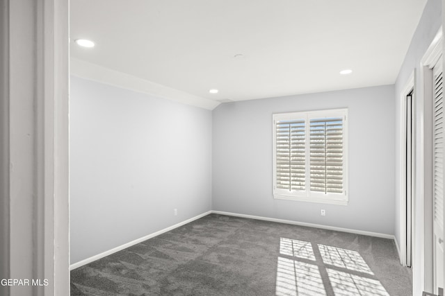 unfurnished bedroom with lofted ceiling and dark carpet