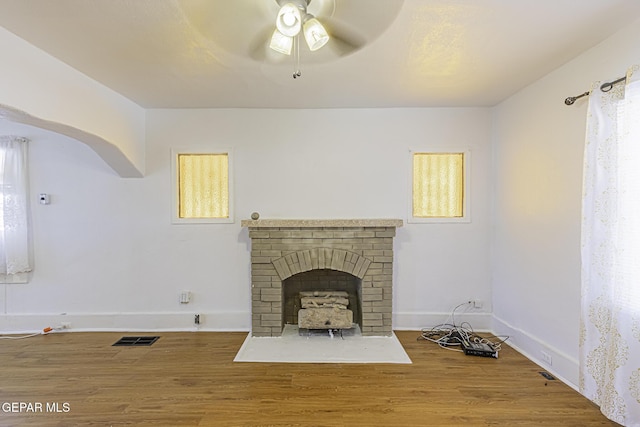 living room featuring hardwood / wood-style flooring, ceiling fan, and a fireplace