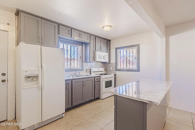 kitchen featuring sink, white appliances, light tile patterned floors, and backsplash