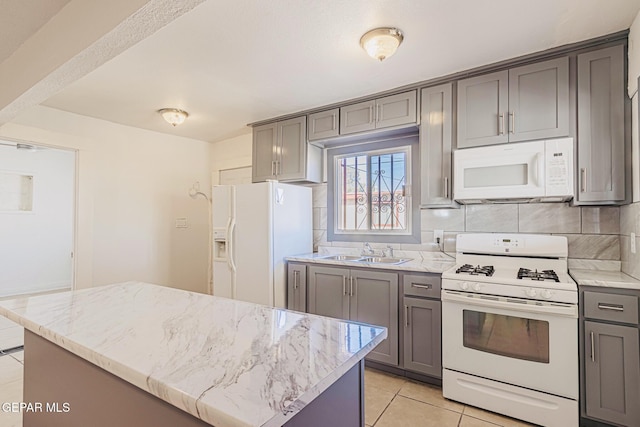 kitchen with sink, gray cabinetry, light tile patterned floors, a kitchen island, and white appliances