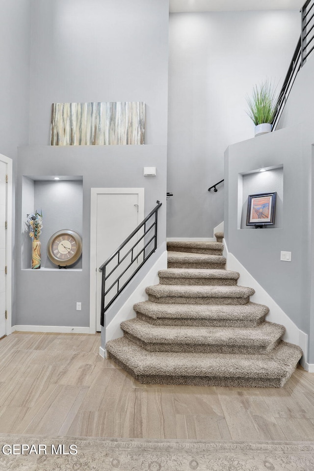 stairway featuring hardwood / wood-style flooring and a high ceiling