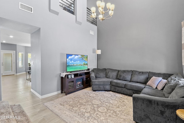 living room featuring a high ceiling, an inviting chandelier, and light hardwood / wood-style floors