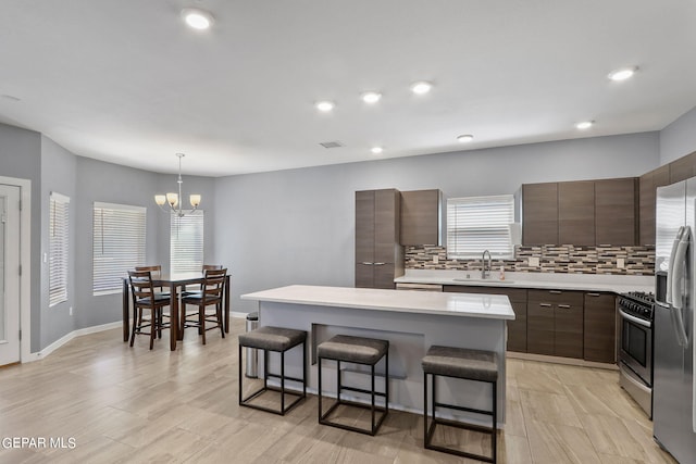 kitchen featuring a kitchen island, sink, backsplash, and dark brown cabinetry