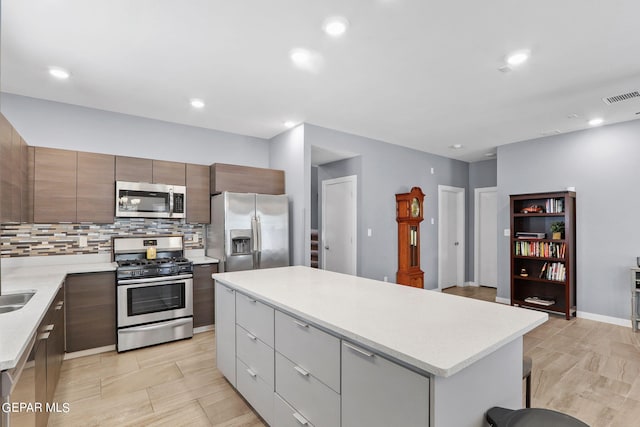 kitchen featuring appliances with stainless steel finishes, a center island, sink, and decorative backsplash