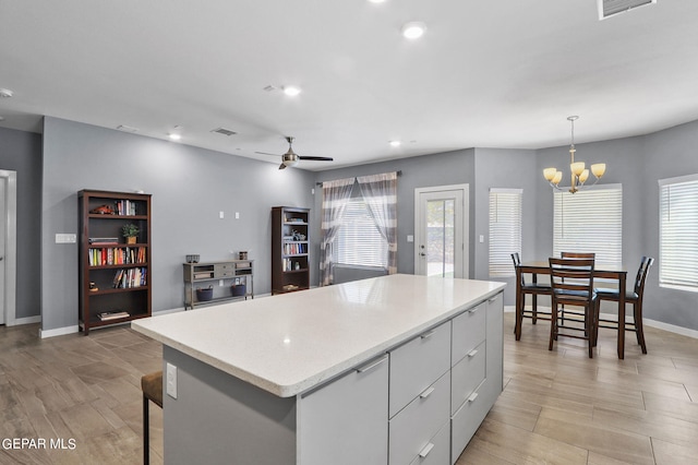 kitchen with pendant lighting, ceiling fan with notable chandelier, and a center island