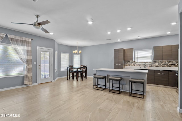 kitchen featuring a breakfast bar, hanging light fixtures, a center island, tasteful backsplash, and dark brown cabinetry