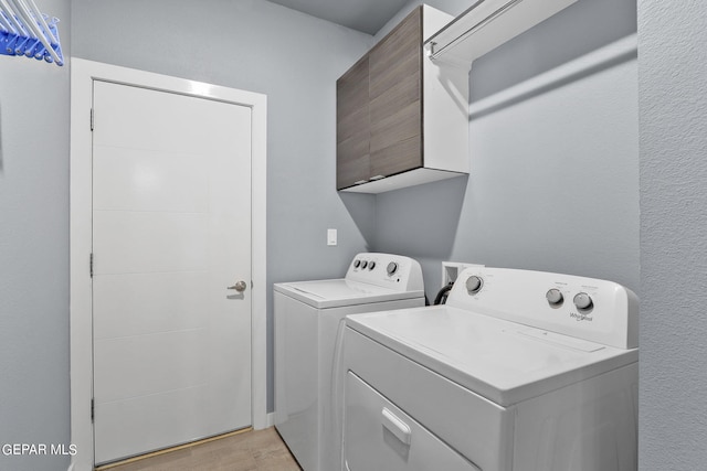 clothes washing area with cabinets, independent washer and dryer, and light hardwood / wood-style floors