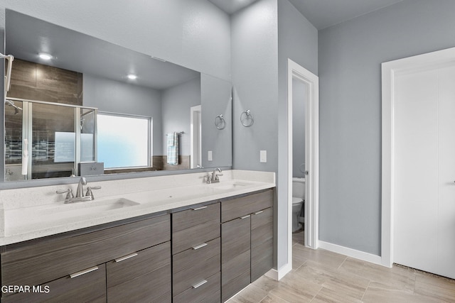 bathroom with a shower with door, vanity, and toilet