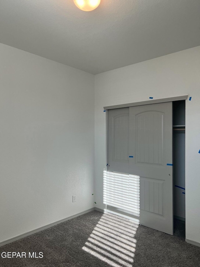 unfurnished bedroom with a closet and dark colored carpet