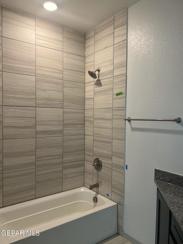 bathroom with tiled shower / bath combo and vanity