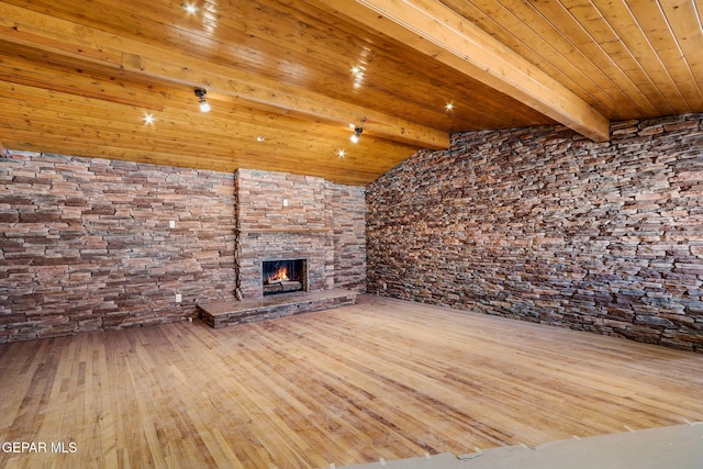 unfurnished living room featuring wood ceiling, vaulted ceiling with beams, a stone fireplace, and wood-type flooring