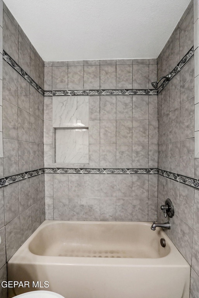 bathroom with tiled shower / bath combo and toilet