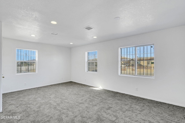 carpeted empty room with a textured ceiling