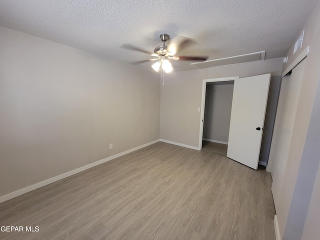 unfurnished bedroom featuring ceiling fan, a closet, a textured ceiling, and light hardwood / wood-style flooring