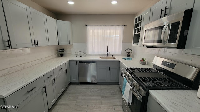 kitchen featuring gray cabinetry, sink, tasteful backsplash, and appliances with stainless steel finishes