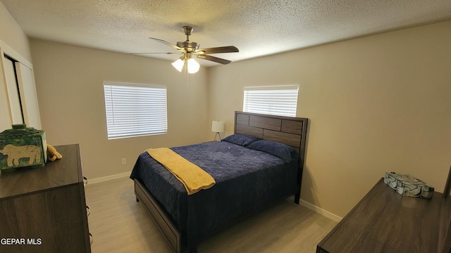 bedroom featuring a textured ceiling, ceiling fan, and light wood-type flooring