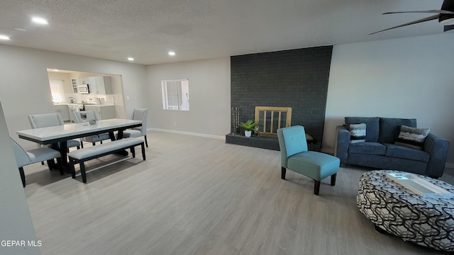 living room featuring a fireplace, light hardwood / wood-style flooring, and a textured ceiling