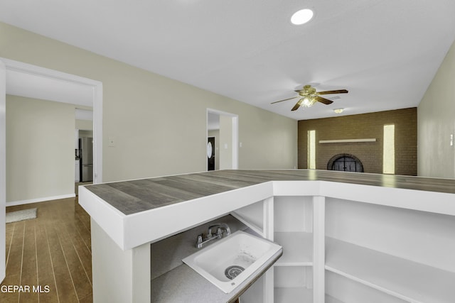 interior space with sink, stainless steel fridge, hardwood / wood-style flooring, ceiling fan, and a fireplace