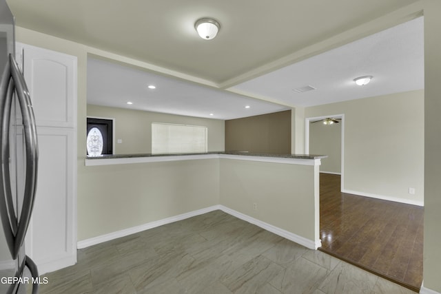 kitchen featuring white cabinetry, stainless steel fridge, and kitchen peninsula