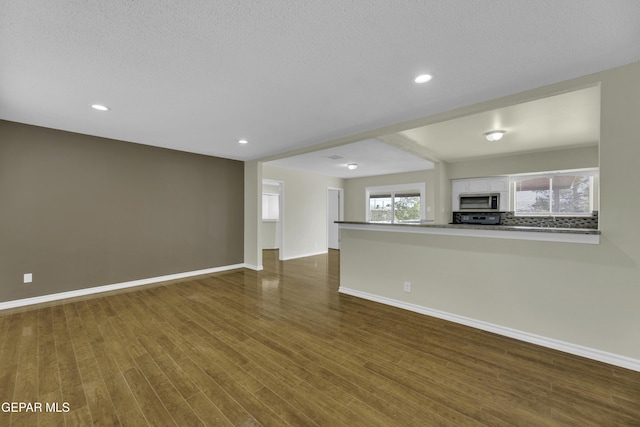 unfurnished living room with dark hardwood / wood-style floors and a textured ceiling