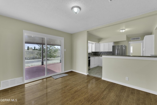 kitchen with stainless steel refrigerator, backsplash, dark hardwood / wood-style flooring, white cabinets, and range