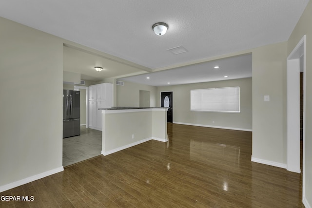 unfurnished living room with dark hardwood / wood-style flooring and a textured ceiling