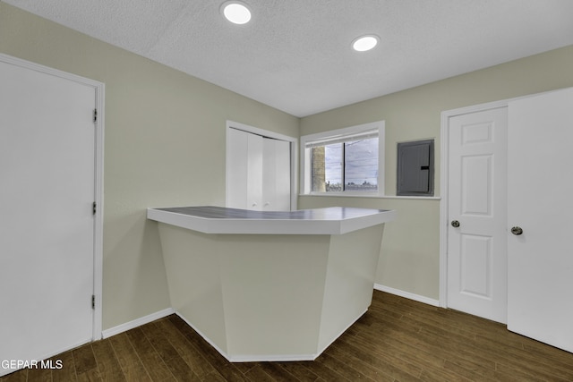 kitchen featuring a textured ceiling, electric panel, dark hardwood / wood-style flooring, and kitchen peninsula