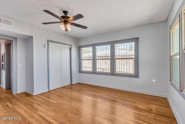 unfurnished bedroom featuring ceiling fan, light hardwood / wood-style floors, and a closet