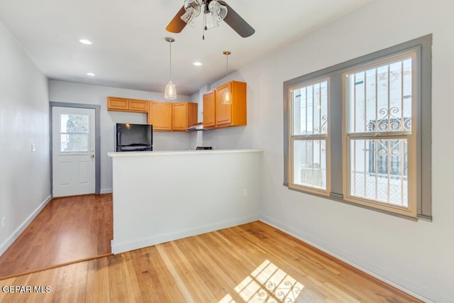 kitchen featuring black fridge, hanging light fixtures, light brown cabinets, light hardwood / wood-style flooring, and ceiling fan