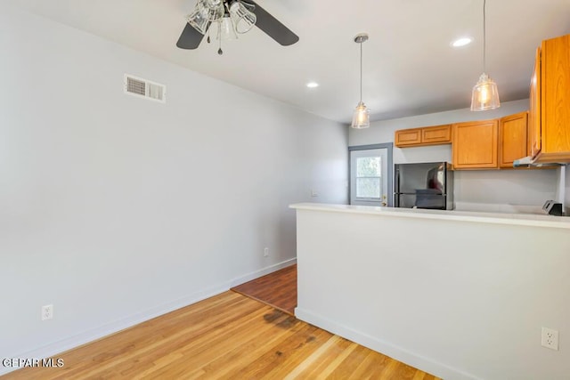 kitchen with black refrigerator, ceiling fan, light hardwood / wood-style flooring, and pendant lighting