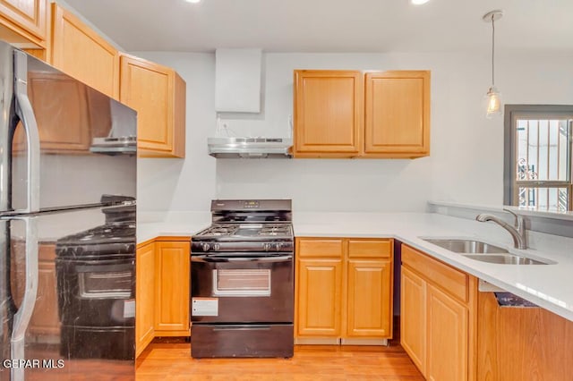 kitchen featuring pendant lighting, sink, black range with gas stovetop, stainless steel fridge, and light hardwood / wood-style floors