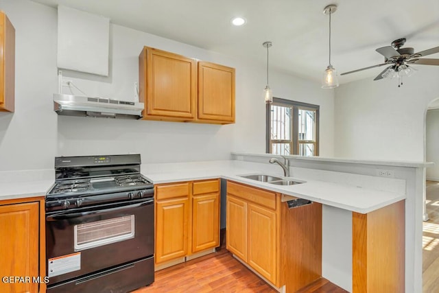 kitchen featuring sink, kitchen peninsula, black gas range, and light wood-type flooring