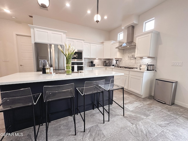 kitchen featuring white cabinets, a center island with sink, wall chimney exhaust hood, and appliances with stainless steel finishes