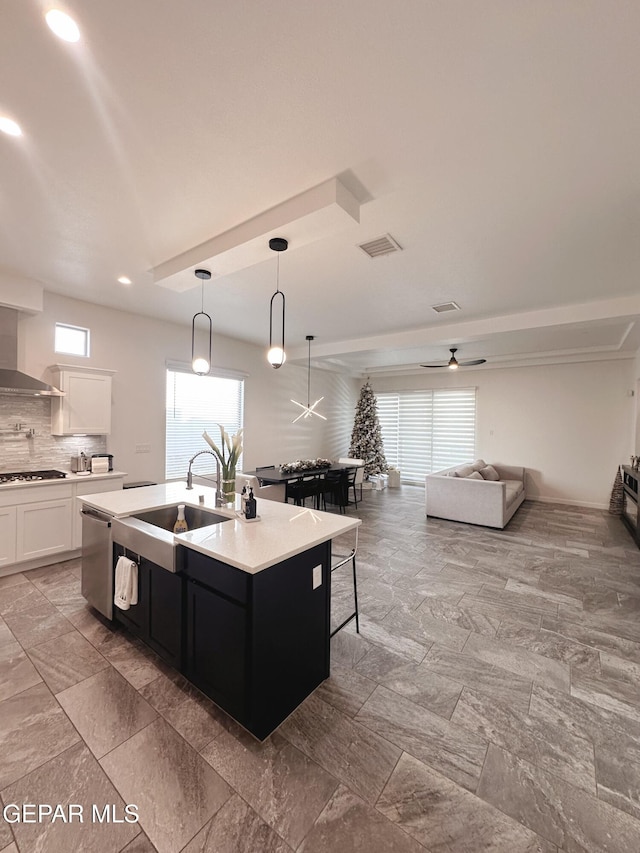 kitchen featuring pendant lighting, sink, white cabinets, gas stovetop, and a center island with sink