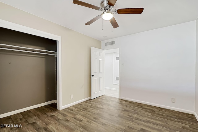 unfurnished bedroom with dark hardwood / wood-style floors, a closet, and ceiling fan