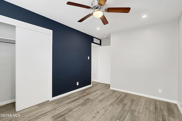 unfurnished bedroom featuring ceiling fan, a closet, and light wood-type flooring