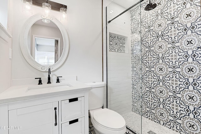 bathroom with vanity, toilet, and tiled shower