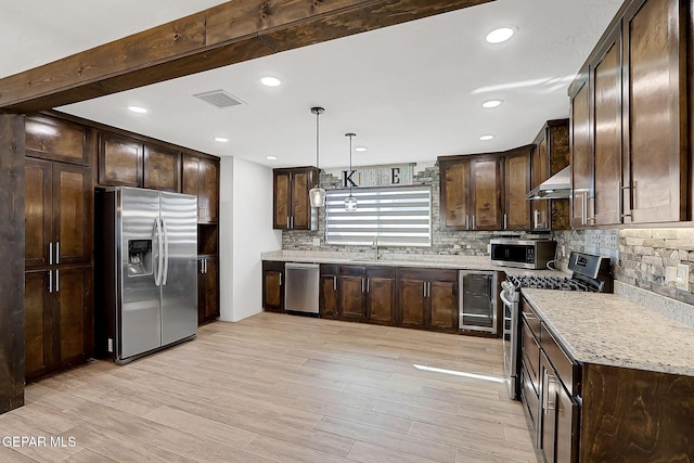 kitchen featuring appliances with stainless steel finishes, backsplash, dark brown cabinetry, decorative light fixtures, and beverage cooler