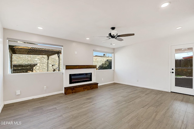 unfurnished living room featuring ceiling fan and light wood-type flooring