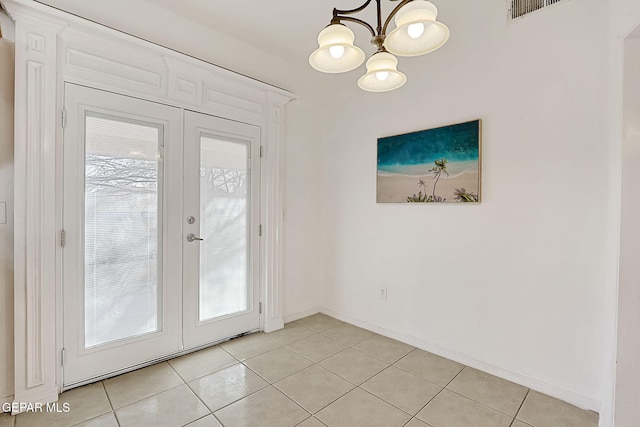 entryway featuring light tile patterned flooring, a notable chandelier, and french doors