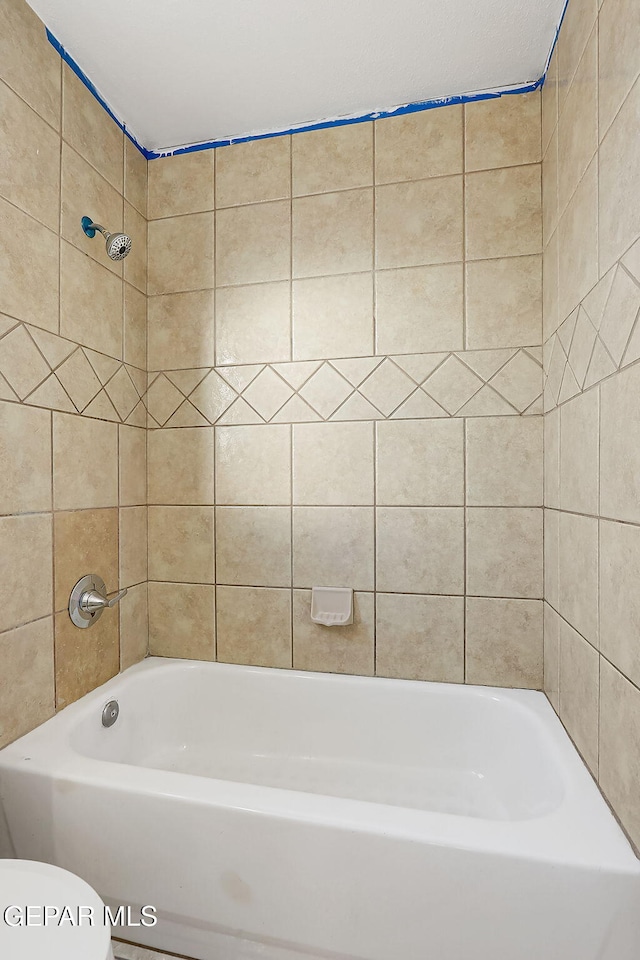 bathroom featuring tiled shower / bath combo and toilet