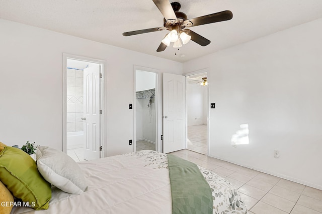 tiled bedroom featuring connected bathroom, a spacious closet, and ceiling fan