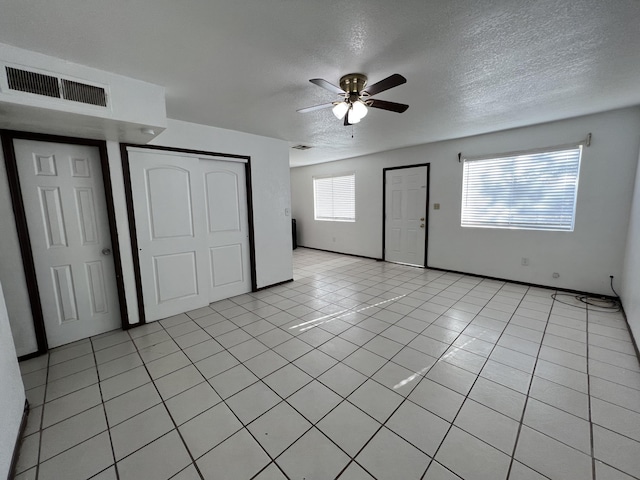 unfurnished bedroom with light tile patterned flooring, ceiling fan, and a textured ceiling