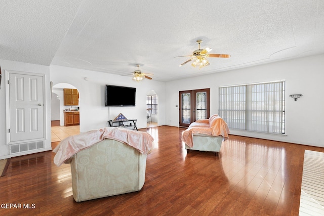 living room featuring hardwood / wood-style flooring, ceiling fan, and a textured ceiling