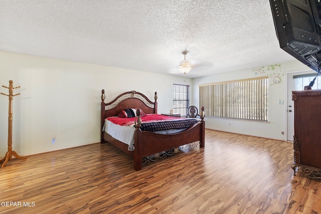 bedroom featuring ceiling fan, hardwood / wood-style flooring, and a textured ceiling