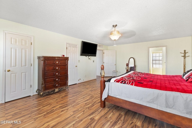 bedroom with ceiling fan, hardwood / wood-style flooring, and a textured ceiling