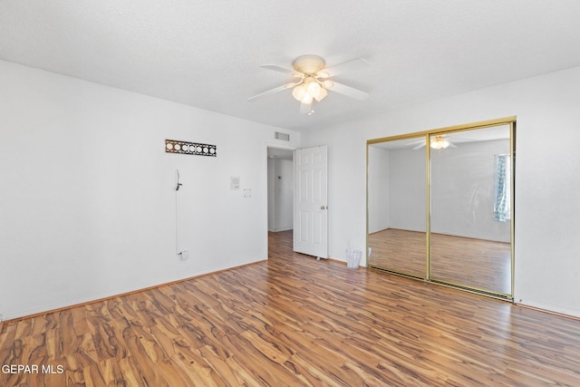 unfurnished bedroom with hardwood / wood-style floors, a closet, a textured ceiling, and ceiling fan