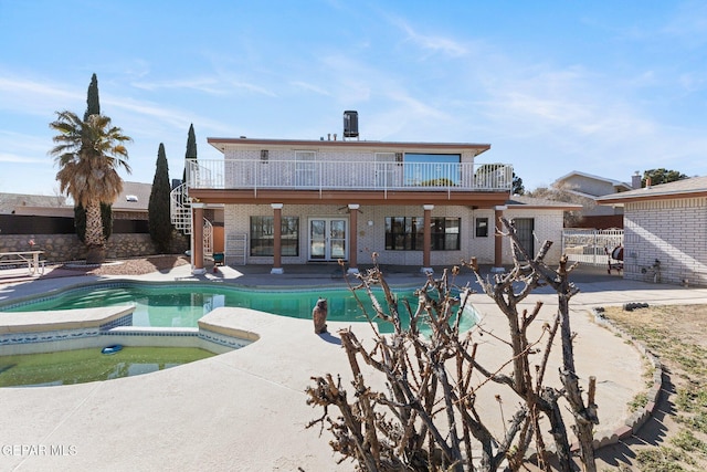 rear view of property featuring a balcony, a swimming pool with hot tub, and a patio area